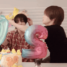 a person holding a number 3 balloon next to another person holding a number 20 balloon