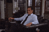 a man sits in a chair with a glass of whiskey in his hand