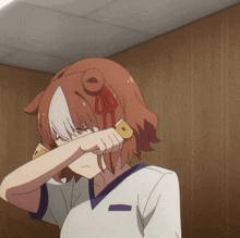 a girl covering her face with her hand in front of a brown wall