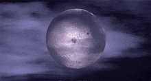 a full moon in a cloudy sky with a purple background