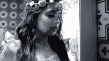 a woman with a flower crown on her head stands in front of a wall with playing cards on it