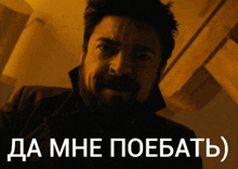 a man with a beard is standing in front of a sign that says да мне поебать