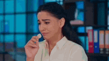 a woman in a white shirt is crying and holding a piece of paper in her hand .
