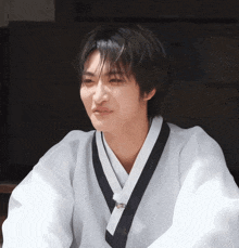 a young man wearing a white kimono with a black collar