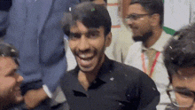 a man in a black shirt is smiling in a crowd