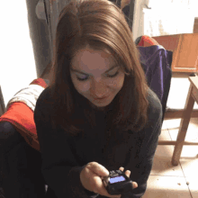 a woman is smiling while holding a cell phone in her hand