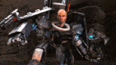 a bald man is standing next to a robot with a shield