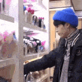 a man wearing a blue hat and a black jacket is standing in front of a store shelf .