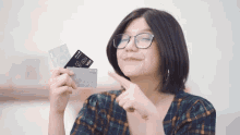 a woman wearing glasses holds a visa card in her hand