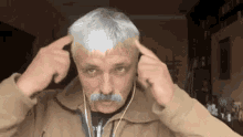 a man with a mustache is wearing headphones .