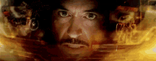 a close up of a man 's face with a beard and mustache in a dark room surrounded by fire .