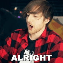 a man wearing a red and black plaid shirt says " alright "
