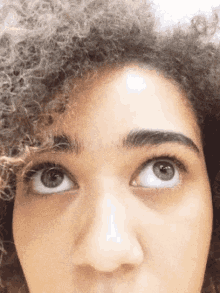 a close up of a woman 's face with curly hair looking up at the camera