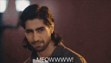 a man with long hair and a beard is saying meowwww