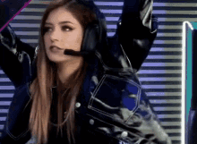 a woman wearing headphones and a leather jacket is standing in front of a wall .