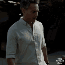 a man in a white shirt is standing in front of a sign that says " the affair "