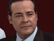 a man in a suit and tie looks at the camera with a sad look on his face