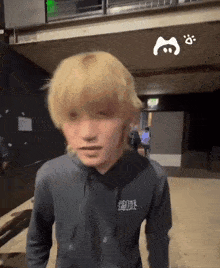 a man with blonde hair is wearing a black hoodie with chinese writing on it