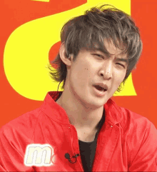 a man wearing a red jacket with the letter m on the front