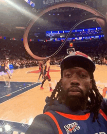 a man wearing a nyc jersey is taking a selfie at a basketball game