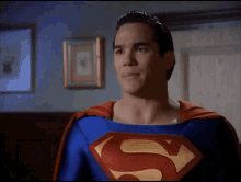 a man in a superman costume stands in front of a wall with pictures on it
