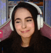 a woman wearing headphones is smiling in front of a shelf with a game called life
