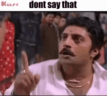 a man with a mustache is making a funny face while pointing his finger at the camera .