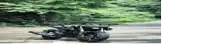 a black motorcycle is driving down a road next to a forest .
