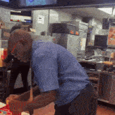 a man in a blue shirt is working in a kitchen with a sign that says ' a ' on it