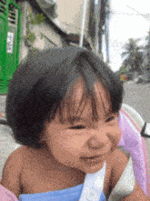 a baby is smiling in front of a green door that says ' ec ' on it