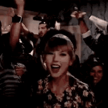 a woman is dancing with her hands in the air in a crowd of people .