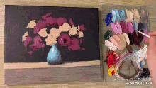 a painting of flowers in a blue vase next to a palette of colors