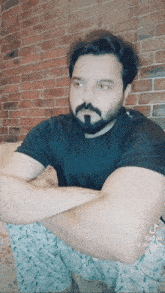 a man with a beard sits with his arms crossed