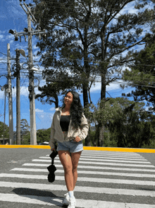 a woman in shorts and a white jacket crosses a street