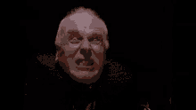 a close up of a man 's face with his mouth open in a dark room .