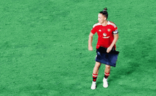 a female soccer player is standing on a field holding a flag and waving her hand .
