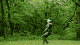 a man in a green suit is standing in a field with trees in the background and a red figure in the background