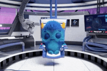 a blue stuffed animal is sitting in a chair in a room with a monitor .