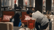 a man is kneeling down next to a woman in a room