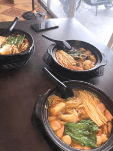 three bowls of food on a table with a phone on the table