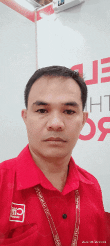 a man wearing a red shirt with a lanyard around his neck that says ' ptc ' on it