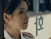 a close up of a woman looking out a window with the letter h on it