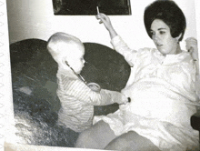 a black and white photo of a baby playing with a stethoscope on a pregnant woman 's belly