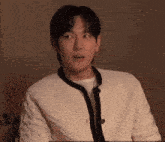 a man wearing a white sweater with a black trim