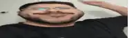 a man with a beard wearing glasses and a black shirt is smiling .
