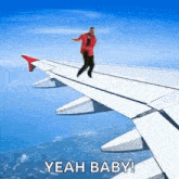 a man is standing on the wing of an airplane and says yeah baby .