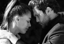 a black and white photo of a man and woman looking at each other .