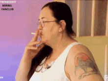 a woman with a tattoo on her arm is smoking a cigarette ..