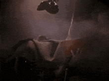a person is laying in a dark room with smoke coming out of the window