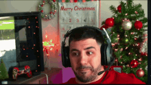 a man wearing headphones stands in front of a merry christmas calendar